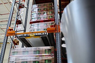 Platformy mobilne wiozą podany przez reach truck ładunek w głąb regału.