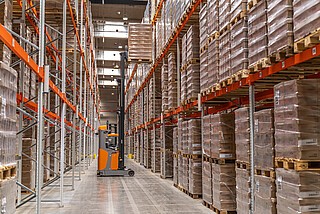 Samojezdne reach trucki transportują ładunki do systemu regałowego wysokiego składowania.